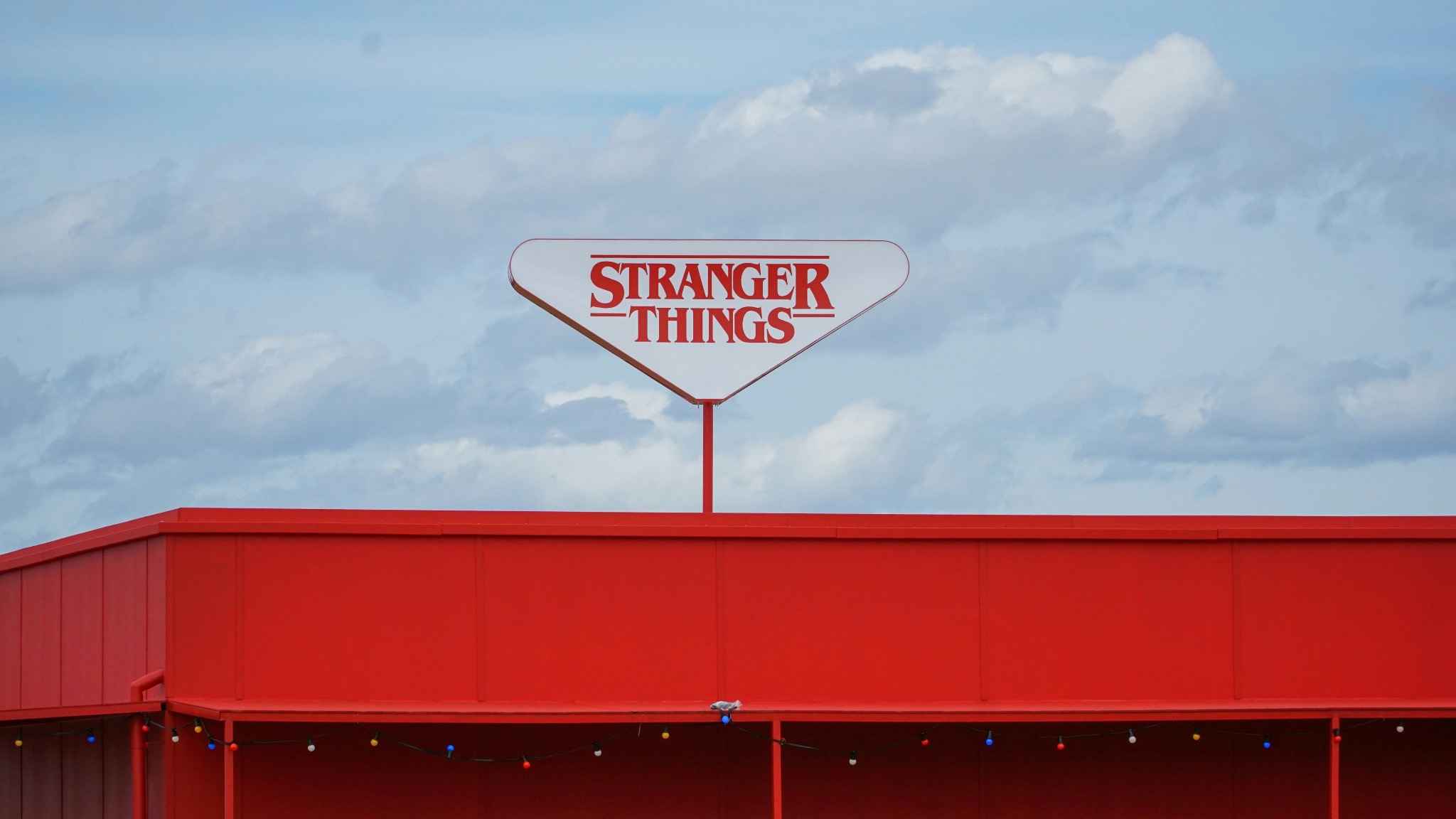 Stranger Things sign on a red building against a cloudy sky — symbolic image used in a psychodynamic therapy blog exploring trauma, identity, and the unconscious at Serenity of Mind Therapy in Haywards Heath and Crowborough, Sussex.