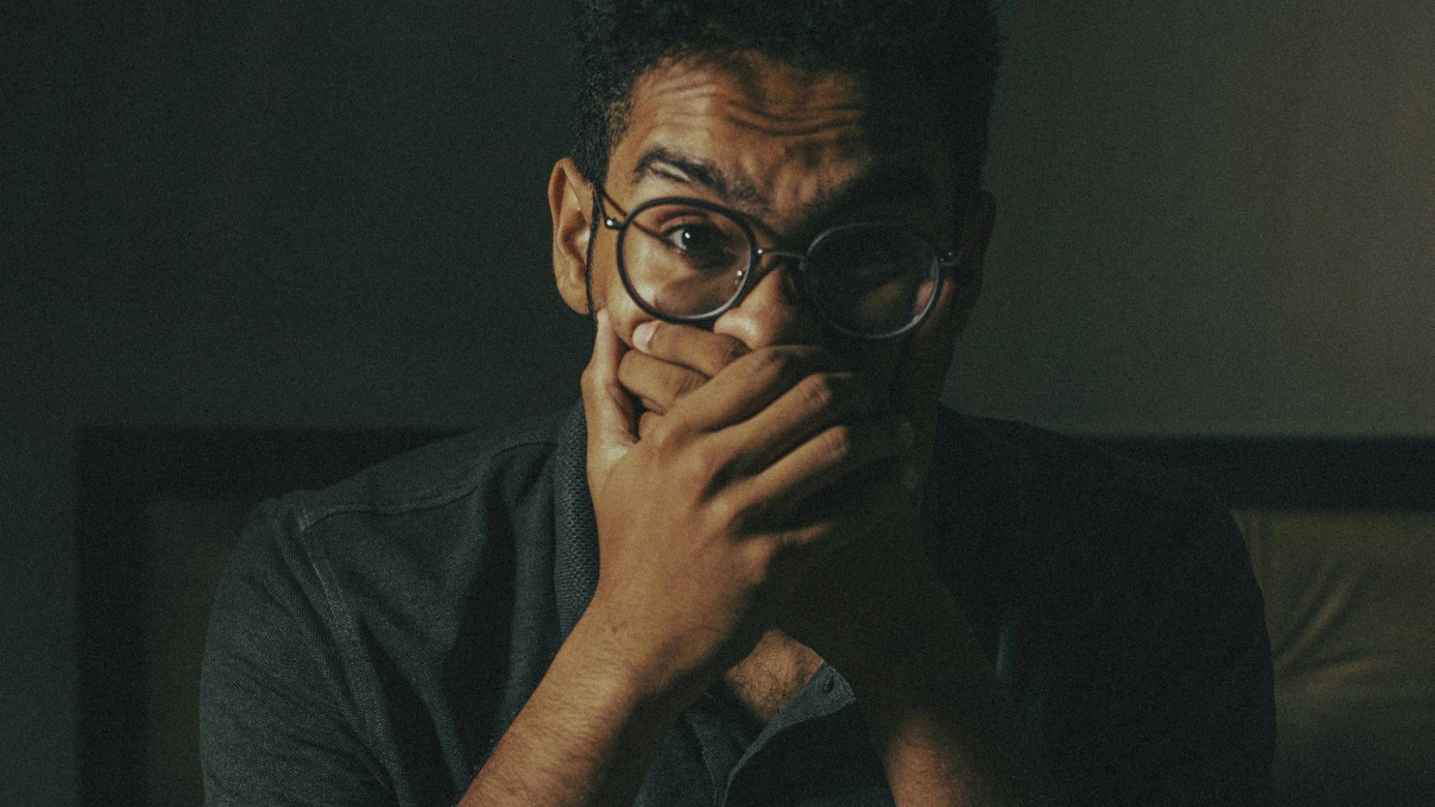 Man covering his mouth with his hand, looking anxious and overwhelmed, representing anxiety symptoms and the need for counselling and psychodynamic therapy.