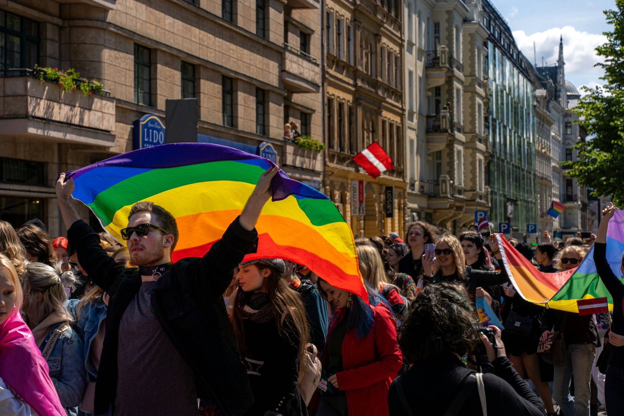 LGBTQIA+ pride march with people holding rainbow flags in a city street, representing identity, community and inclusion