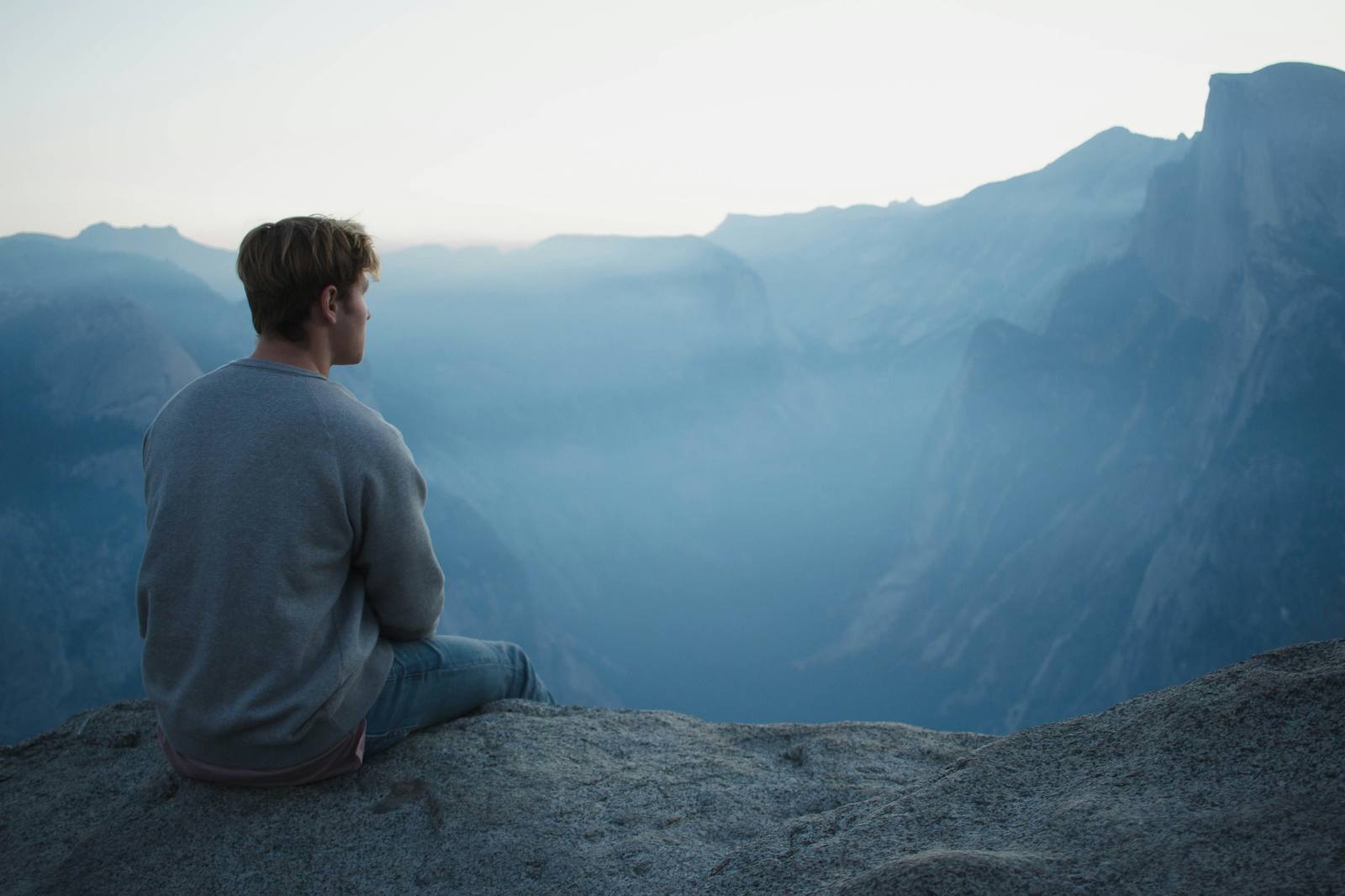 Person sitting alone overlooking mountains representing separation anxiety, emotional isolation, attachment anxiety, and psychodynamic therapy support.