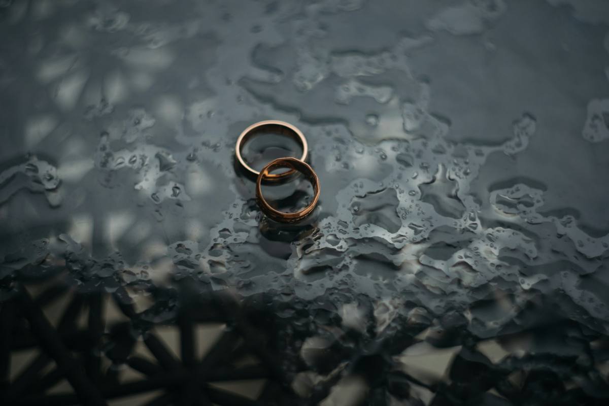 Wedding rings resting on a rain-covered surface symbolising separation, divorce, grief, relationship loss and emotional healing through counselling.